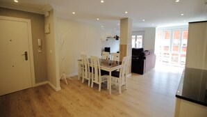 A spacious living area with a dining table and chairs, a sofa, and a kitchen area.