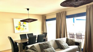 A living room with a sofa, coffee table, dining table, chairs, and a ceiling fan. - AMAZING SEA VIEW LUXURY APARTMENT- WITH SUN DRENCHED SPACIOUS TERRACE/FREE WiFi (Gran Tarajal, Tuineje)