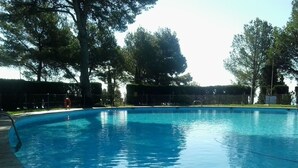 A clear blue swimming pool surrounded by trees and a fence.
