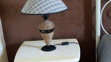 A bedside table with a lamp, drawers, and a power cord.
