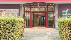 A hotel entrance with a glass door, a red awning, and a sign above the door.
