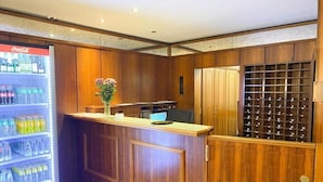 A reception area with a Coca-Cola refrigerator, a desk with a vase of flowers, and a wine rack.