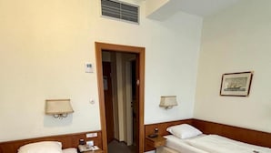 A hotel room with two beds, a nightstand with a phone, a lamp, and a picture on the wall.