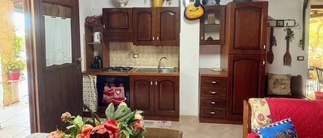 A kitchen with wooden cabinets, a marble countertop, and a dining area with a red sofa.
