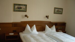 Une chambre d’hôtel avec une tête de lit en bois, deux tables de chevet et deux tableaux encadrés accrochés au mur.