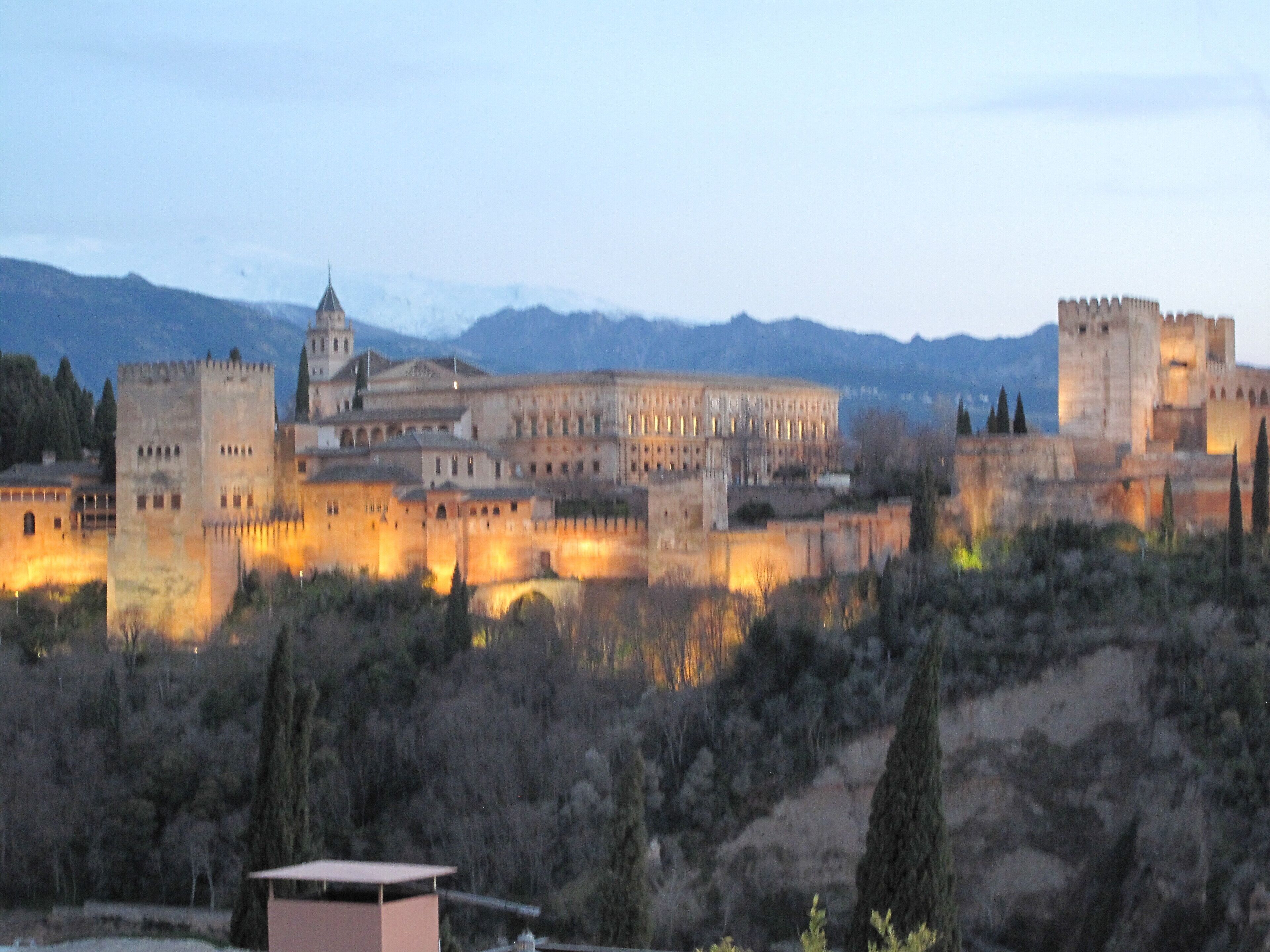A historic castle complex with multiple towers and fortified walls, surrounded by a hilly landscape.