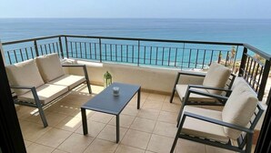 Ein Balkon mit Blick auf den Ozean, ausgestattet mit einem Tisch und Stühlen.