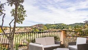 Un espacio de estar al aire libre con mobiliario de mimbre y vistas a un pueblo en la ladera.