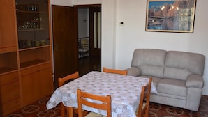 Un comedor con una mesa dispuesta para cuatro personas, un sofá y un aparador con puertas de vidrio.