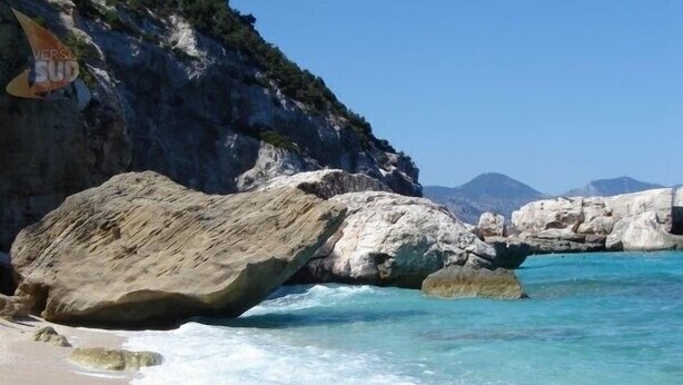 Paesaggio costiero con grandi rocce e acqua turchese cristallina.