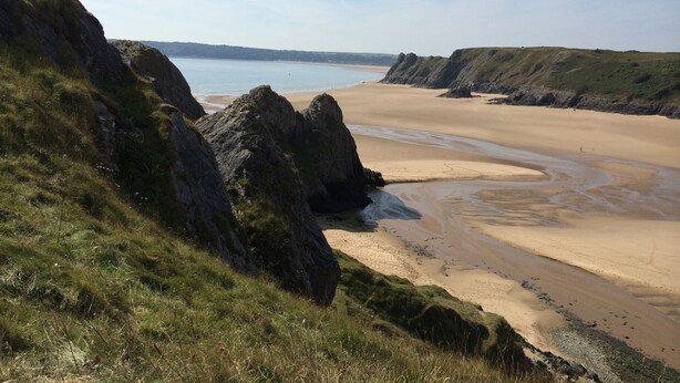 Eine Küstenlandschaft mit felsigen Klippen und einem Sandstrand.