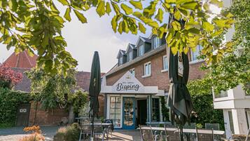 A hotel named 'Hotel Landhaus Bisping' with outdoor seating and a brick facade.