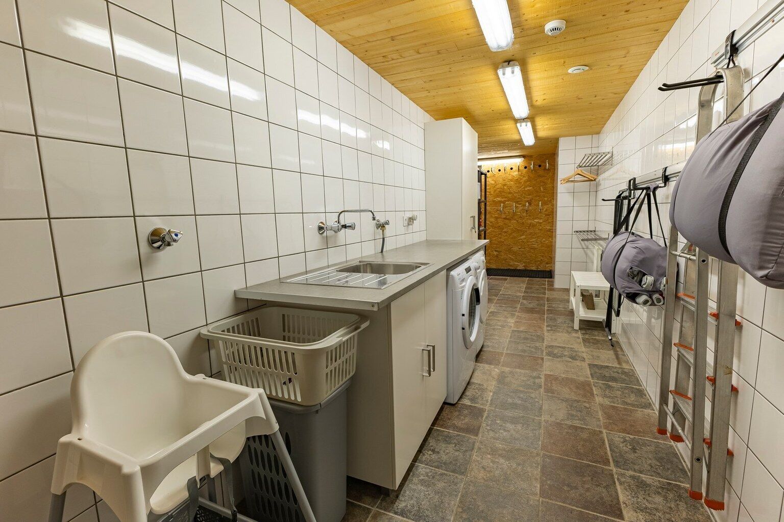 A laundry room with a washing machine, drying racks, and a sink.