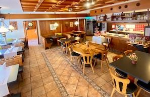 A restaurant interior with wooden tables and chairs, a tiled floor, and a bar area with bottles. - Hotel Zum Roten Lv Wen (Hildisrieden)