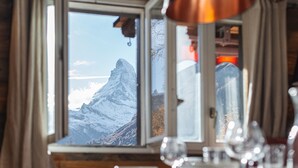 A dining area with a view of a snow-capped mountain through a window.