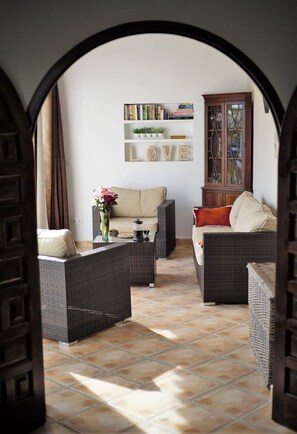A cozy living area with wicker furniture, a bookshelf, and a cabinet. - Luxury Detach Villa, Air Con, Private Pool with sun all day, Stunning Sea Views. (Teulada)