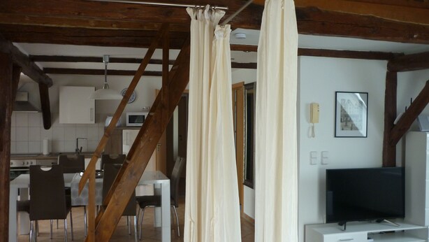 Une cuisine moderne avec des meubles blancs, un four à micro-ondes et un coin repas avec des chaises.