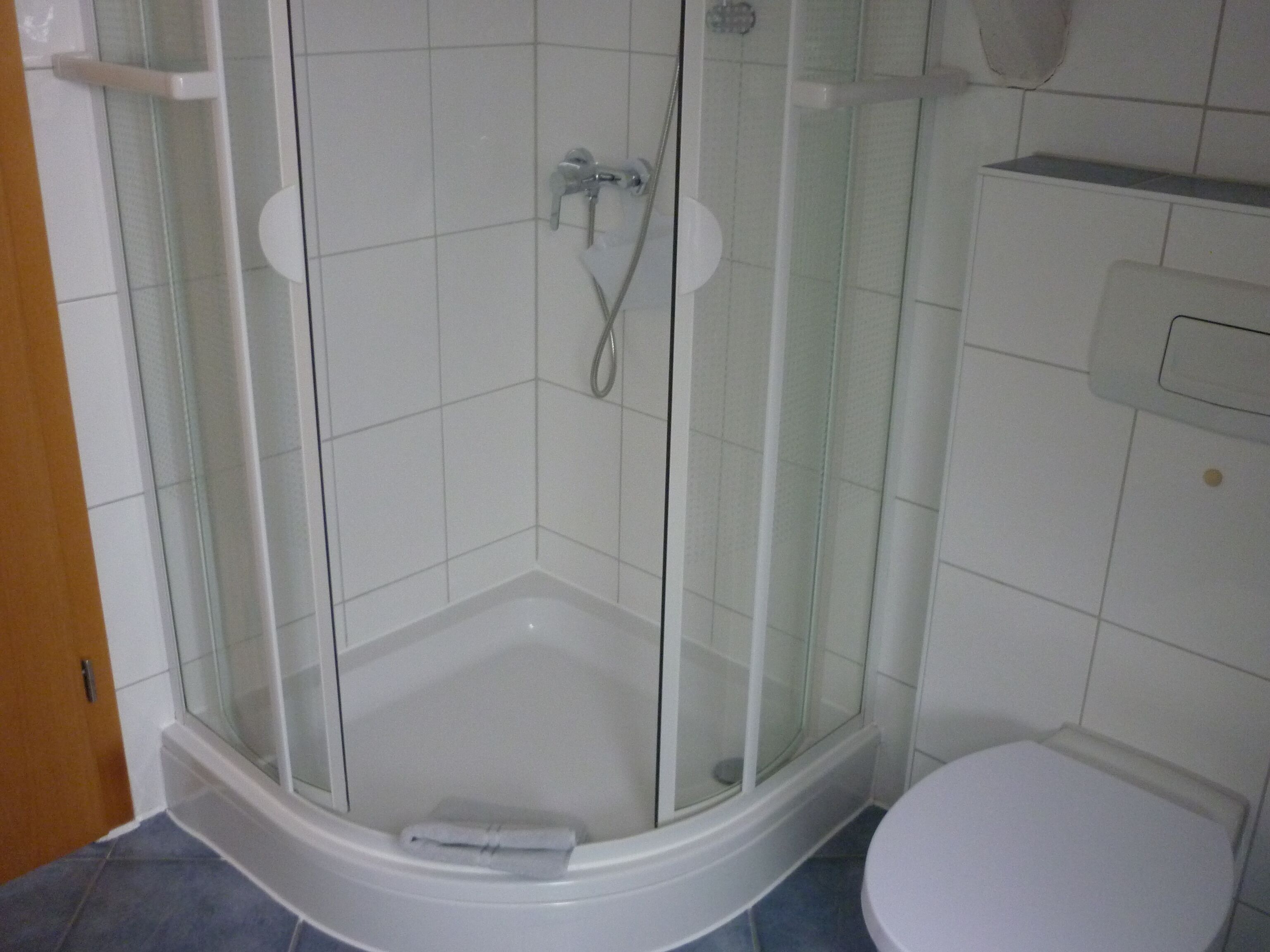 Een douche met glazen wanden, een witte badkuip en een wit toilet.
