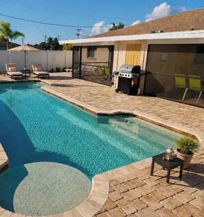 A rectangular swimming pool with a textured edge, surrounded by a brick patio.