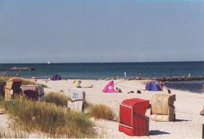A beach with tents and beach huts, a clear sky, and a calm sea. - child and dog friendly holiday home complex (Heidkate)