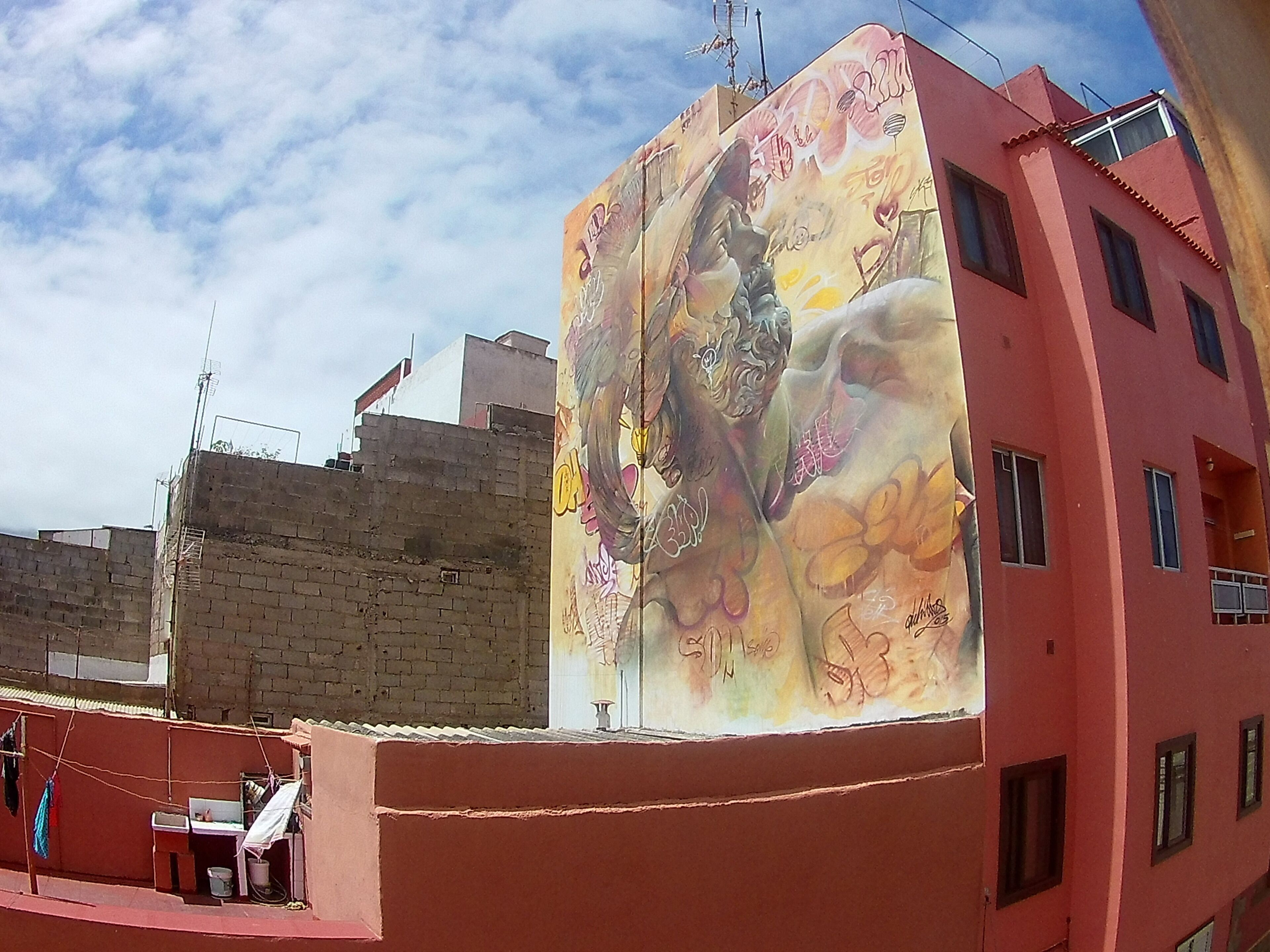 Un bâtiment dont la façade est ornée d’une fresque représentant une femme et des fleurs.