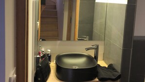 Un baño con un lavabo negro, un espejo y un perchero para toallas.