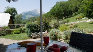 Une table avec un plateau en verre, une tasse rouge, une assiette blanche ornée de motifs floraux et un saladier rempli de fruits.