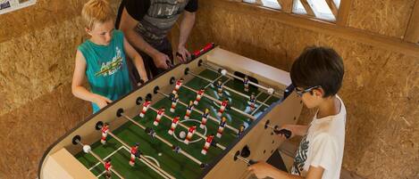 A foosball table in a room with wooden walls and a window with a lattice design.