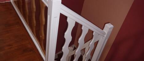 A wooden staircase with white balusters and a red wall.