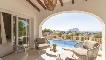 Un balcón con piscina, mobiliario de mimbre y vistas a un paisaje montañoso.
