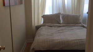 Una camera da letto con un letto, una lampada da terra e una finestra con tende.