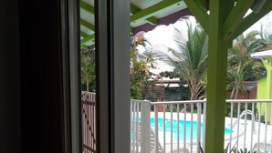 Un espace extérieur abrité comprenant une piscine, des plantes en pot et une clôture blanche.