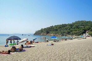 A beach with people sunbathing and swimming, umbrellas, and boats in the water. - 1500€/MONTH FROM NOVEMBER TO THÉ END OF MARCH VILLA 100M BEACH ACCESS DIREK WIFI (Le Lavandou)