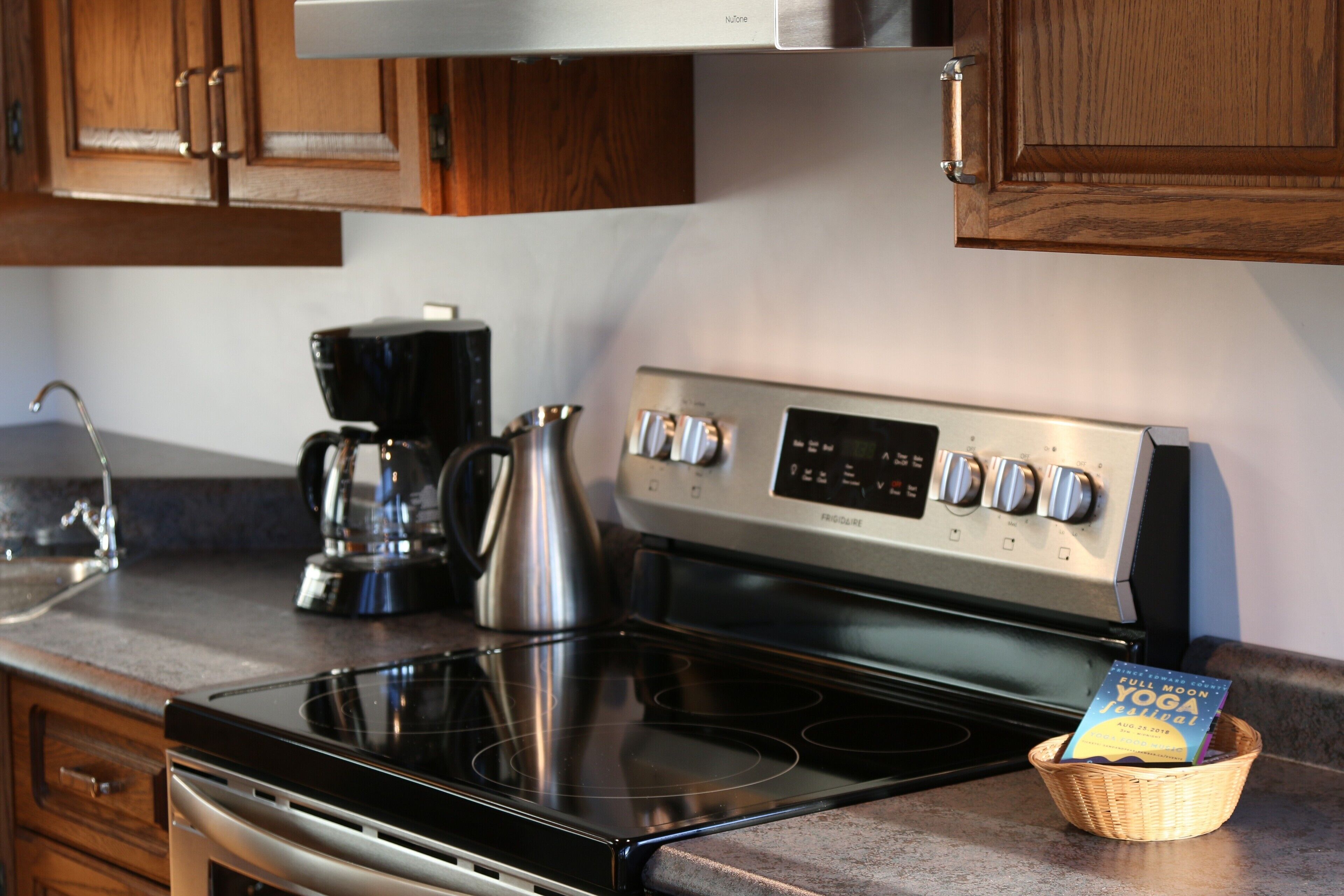 A kitchen with a stainless steel stove, wooden cabinets, and a coffee maker.