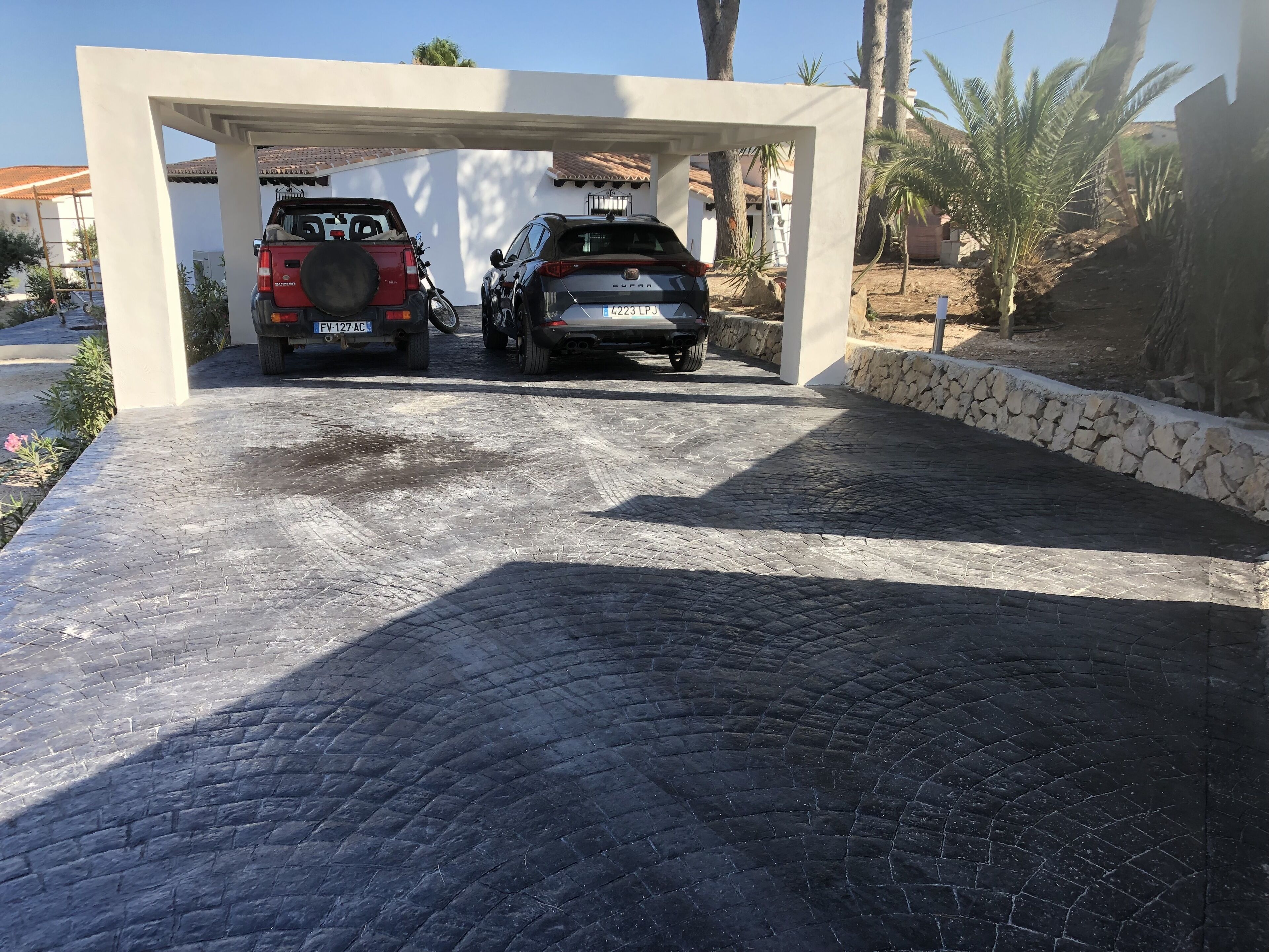 A covered parking area with two SUVs parked under a white structure.