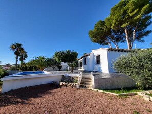 A white villa with a pool, stone steps, and a garden.