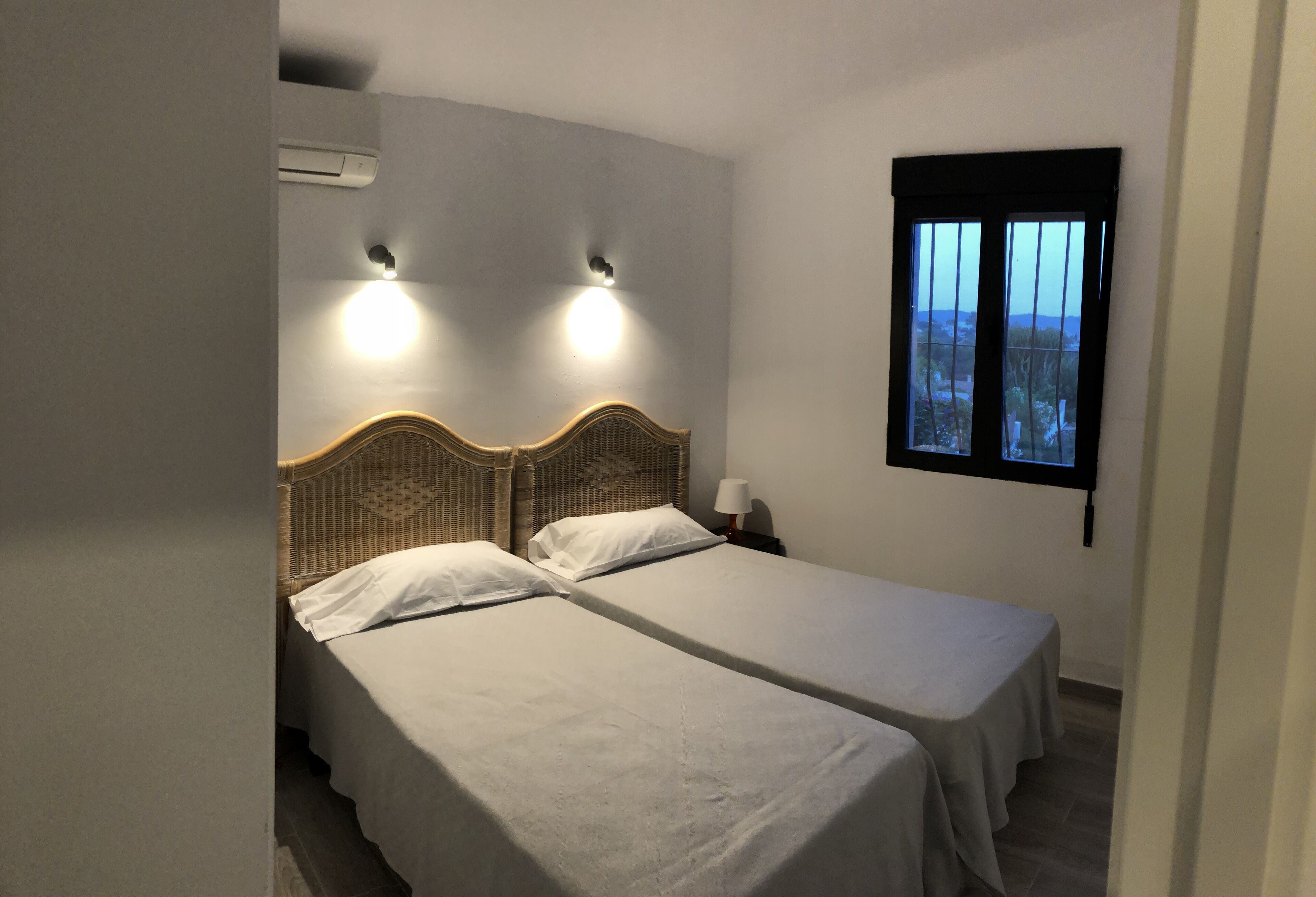 Ein Zimmer mit zwei Einzelbetten, einem Fenster mit Blick und einer Wand-Klimaanlage.