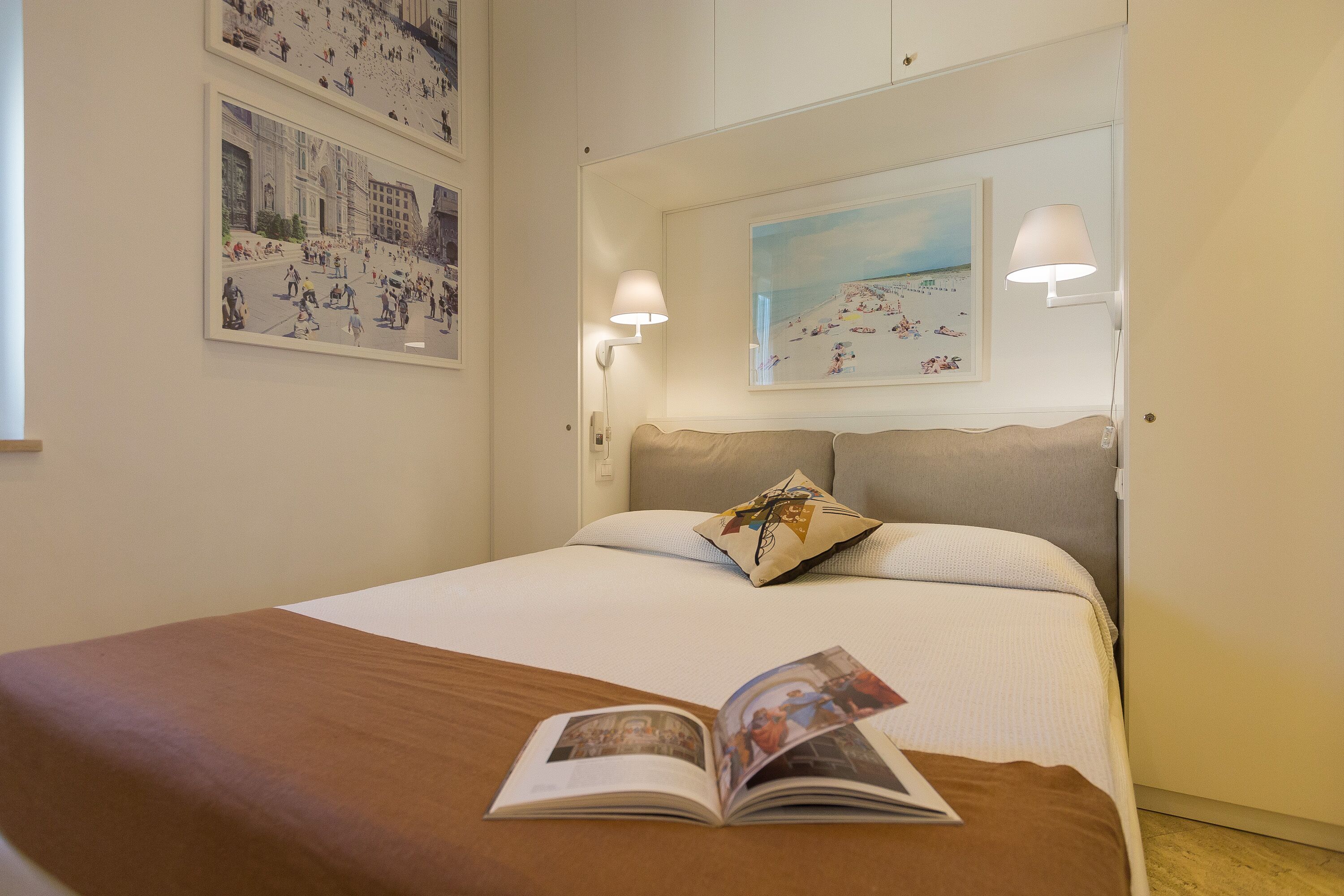 Una cama bien hecha con una colcha marrón, una almohada y un libro abierto sobre la cama.
