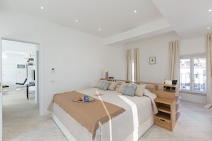 A modern bedroom with a large bed, bedside tables, a desk, and a window with curtains. - Amazing Penthouse Piazza Venezia (Roma)