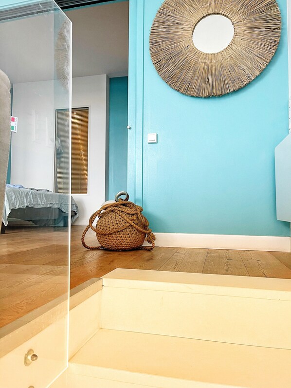 Une pièce avec un mur bleu, un panier en osier et un lit recouvert d’une couverture bleue.
