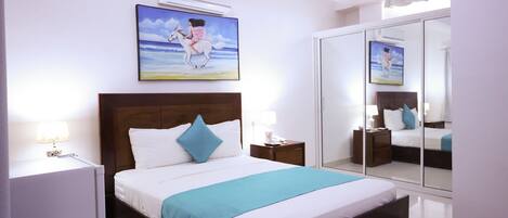 A bedroom with a bed, bedside tables, a mirror, and artwork on the wall.