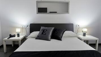 Een netjes ingerichte hotelkamer met een groot bed, twee nachtkastjes, een bedlampje, een telefoon en een kleine spiegel aan de muur.