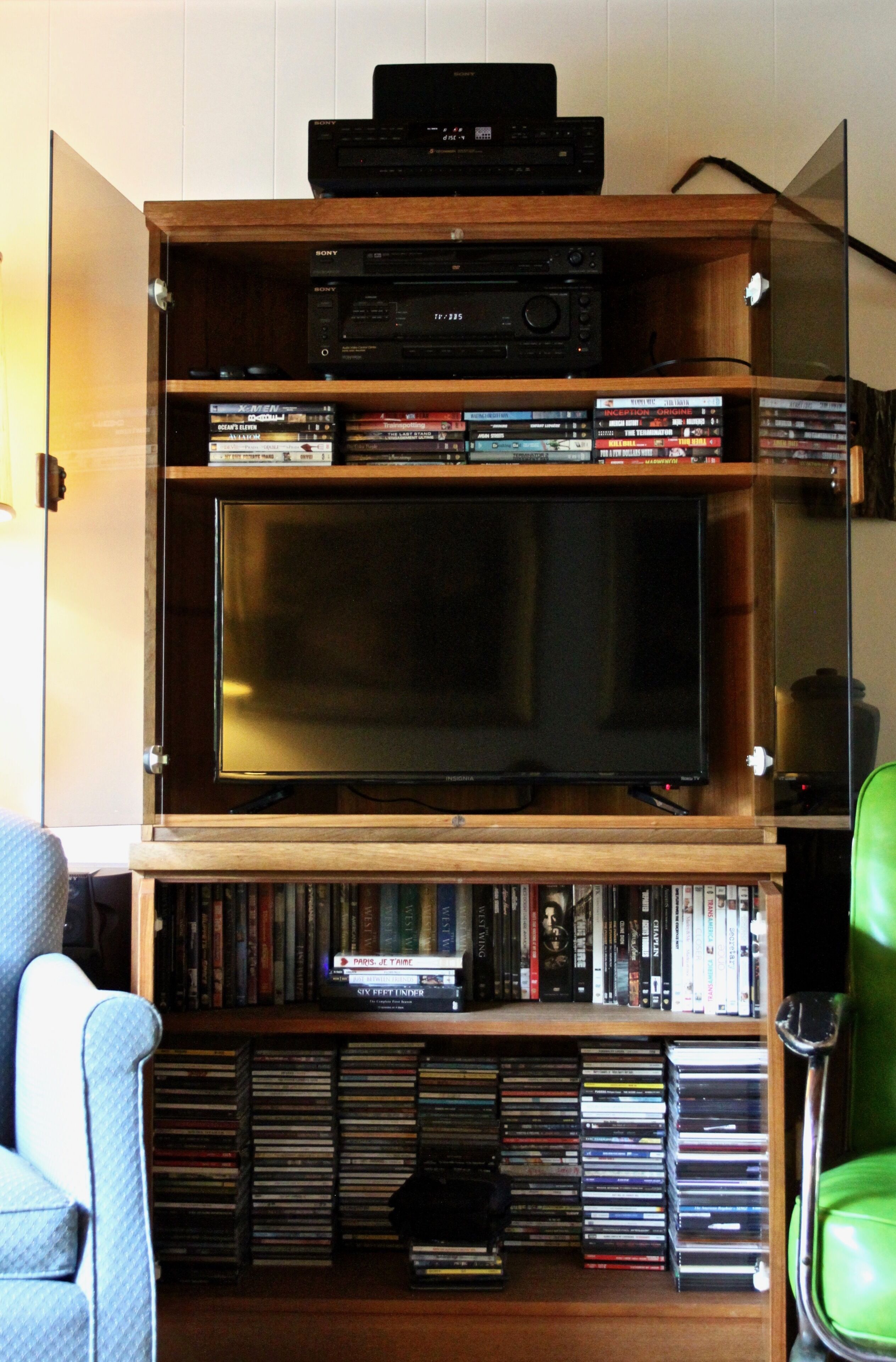 Un meuble de rangement en bois comprenant un téléviseur, un lecteur DVD et divers appareils multimédias.
