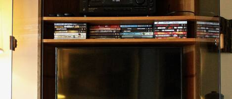 Un meuble de rangement en bois comprenant un téléviseur, un lecteur DVD et divers appareils multimédias.