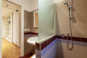 A bathroom with a glass shower enclosure, a sink, and a mirror.