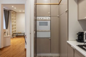 A compact kitchen with a built-in oven, a coffee machine, and a small dining table. - Terrace In The Heart Of City Centre - Wifi, Airconditioning, Washer, Dishawasher (Roma)
