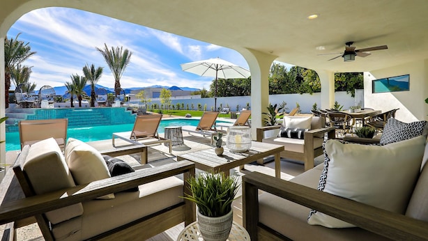 Ein Terrassenbereich im Freien mit Pool, Liegestühlen und einem Esstisch.