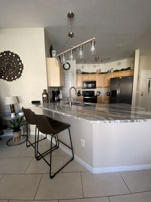 A modern kitchen with a central island, stainless steel appliances, and pendant lighting. - Beautiful 3 Bed 2 Bath Luxury Poolside Condo  (Davenport)