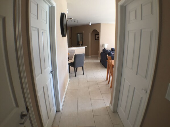 A hallway leading to a dining area with a table and chairs, a sofa, and a lamp. - Beautiful 3 Bed 2 Bath Luxury Poolside Condo  (Davenport)
