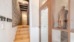 A wooden staircase leading to a room with stone walls and a glass door. - Belomonte Apartments (Porto)